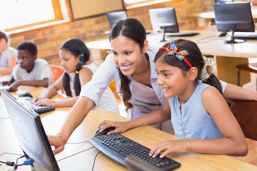 Cute pupils in computer class with teacher at the elementary sch